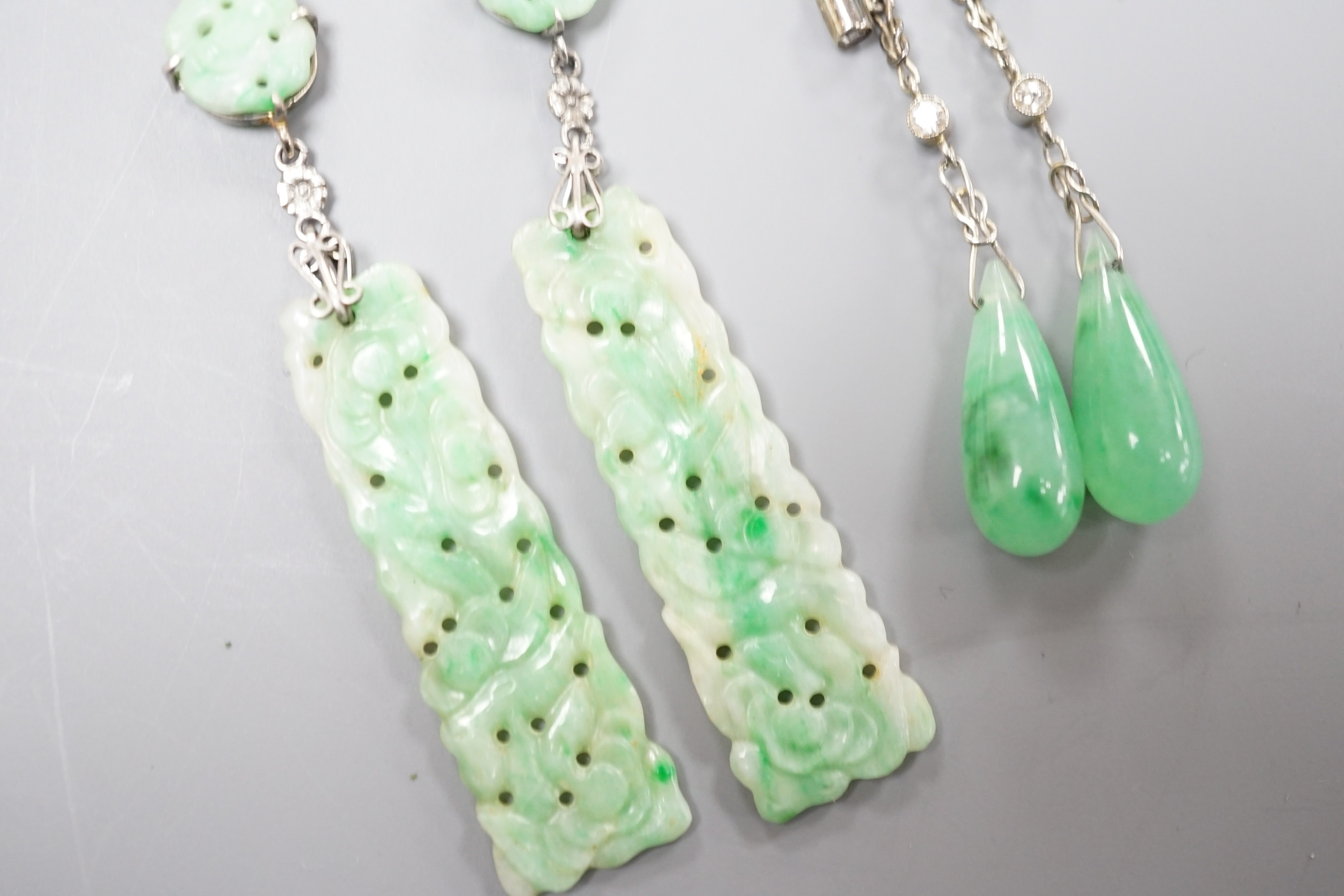 A pair of white metal pair shaped jade and two stone diamond set drop earrings, 37mm and one other pair of carved jade drop earrings, gross weight 8 grams.